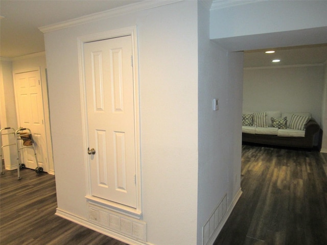 hallway featuring visible vents, dark wood finished floors, baseboards, ornamental molding, and recessed lighting