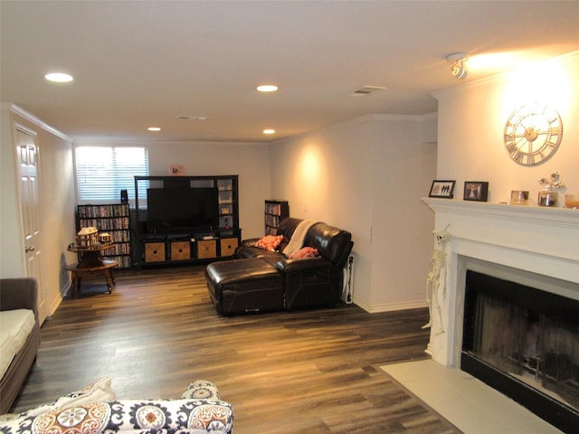 living area with dark wood-type flooring, recessed lighting, ornamental molding, and a fireplace with flush hearth