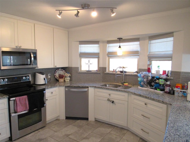 kitchen featuring appliances with stainless steel finishes, ornamental molding, white cabinets, a sink, and light stone countertops