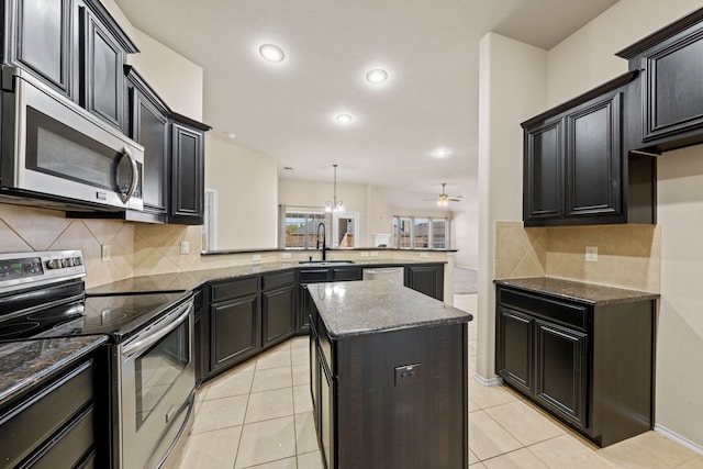 kitchen featuring stainless steel appliances, a peninsula, a kitchen island, a sink, and pendant lighting