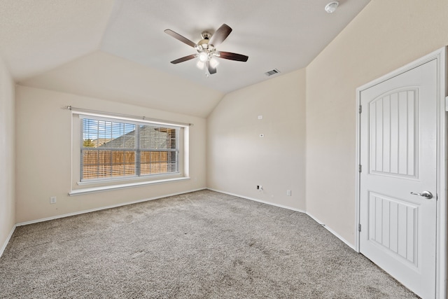 carpeted empty room with vaulted ceiling, ceiling fan, visible vents, and baseboards