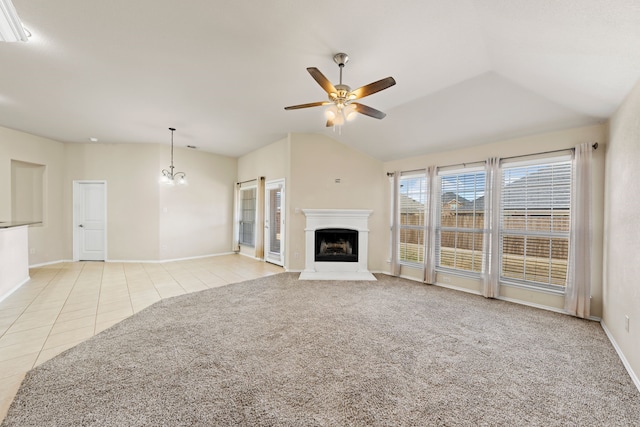 unfurnished living room featuring light tile patterned floors, light colored carpet, lofted ceiling, a fireplace, and ceiling fan with notable chandelier