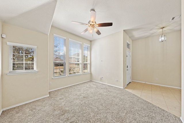 empty room featuring baseboards, visible vents, a ceiling fan, light colored carpet, and light tile patterned flooring