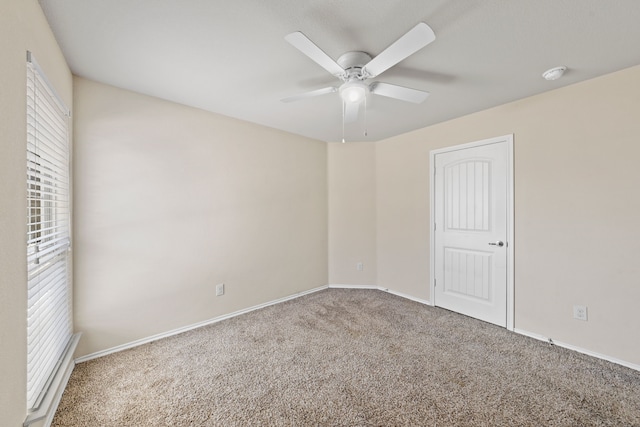 empty room featuring carpet floors, plenty of natural light, baseboards, and a ceiling fan