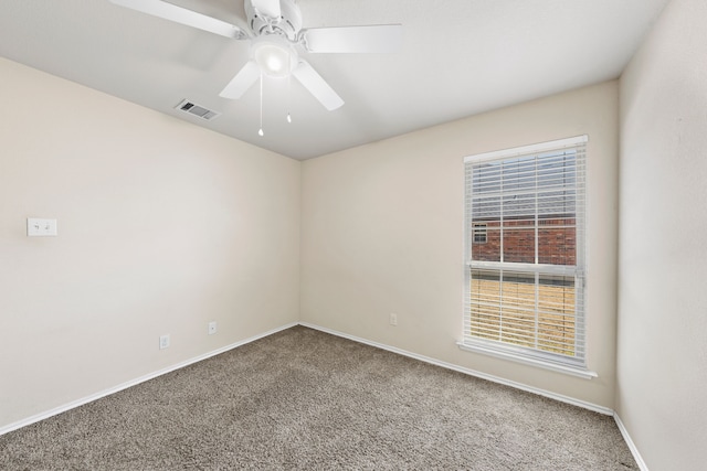 carpeted spare room featuring a ceiling fan, visible vents, and baseboards