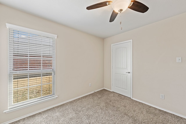 empty room with carpet flooring, ceiling fan, and baseboards