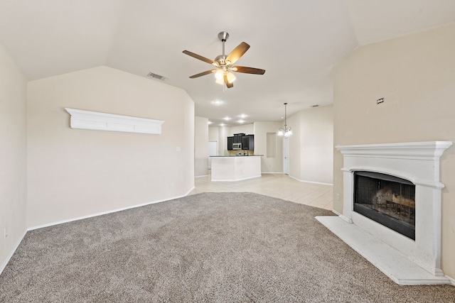 unfurnished living room with light colored carpet, a fireplace with raised hearth, visible vents, vaulted ceiling, and ceiling fan