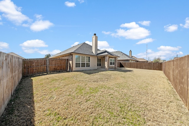 rear view of property with a fenced backyard, a chimney, a lawn, and brick siding