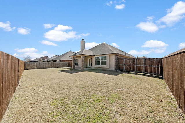 back of property featuring a fenced backyard, brick siding, a chimney, and a patio