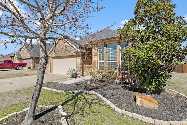 view of property hidden behind natural elements featuring a garage, concrete driveway, stone siding, roof with shingles, and brick siding