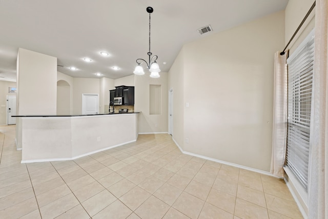 empty room with light tile patterned floors, baseboards, visible vents, arched walkways, and recessed lighting