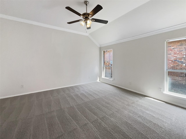 spare room featuring lofted ceiling, ornamental molding, a ceiling fan, dark carpet, and baseboards