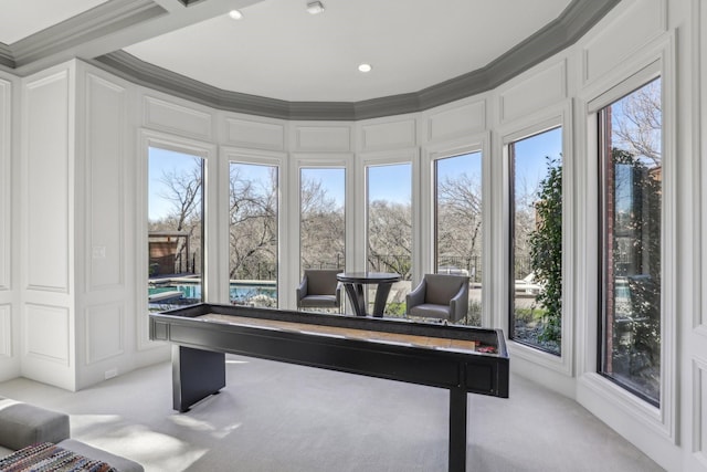 rec room featuring carpet, a decorative wall, and crown molding