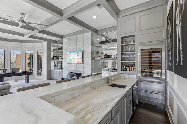 kitchen featuring beverage cooler, coffered ceiling, a sink, and light stone countertops