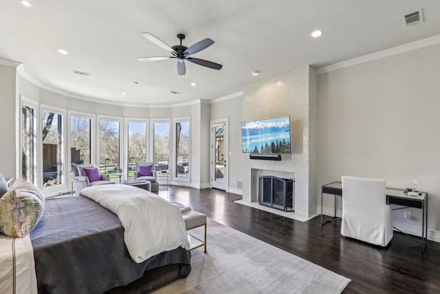 bedroom with visible vents, ornamental molding, a large fireplace, wood finished floors, and baseboards