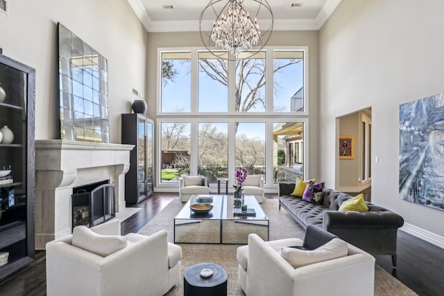 living room featuring plenty of natural light, dark wood finished floors, crown molding, and a high end fireplace