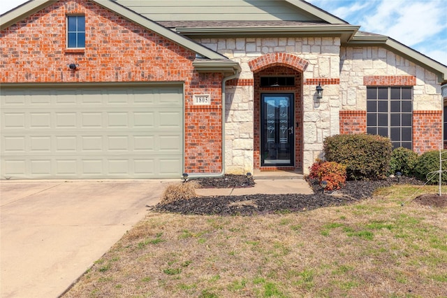 property entrance featuring a garage, concrete driveway, and brick siding