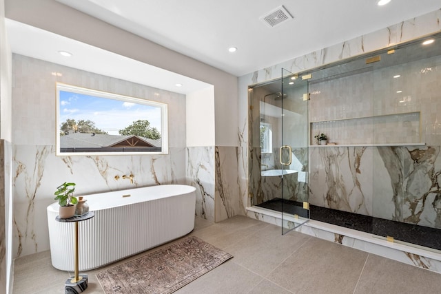 full bath featuring recessed lighting, visible vents, tile walls, a freestanding bath, and a marble finish shower