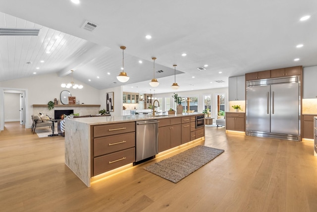 kitchen with a warm lit fireplace, visible vents, lofted ceiling with beams, light wood-style flooring, and appliances with stainless steel finishes