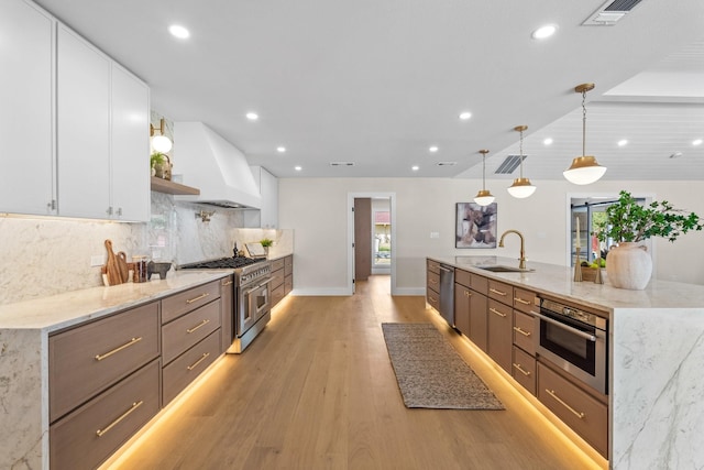 kitchen featuring stainless steel appliances, custom range hood, a sink, and white cabinetry