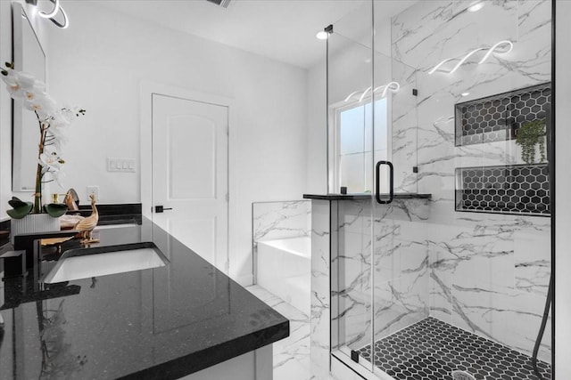 interior space featuring marble finish floor, a tub to relax in, a marble finish shower, and vanity