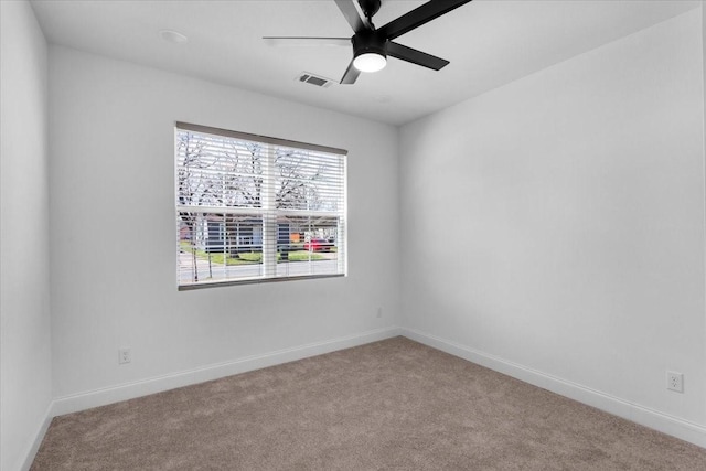 carpeted spare room with ceiling fan, visible vents, and baseboards