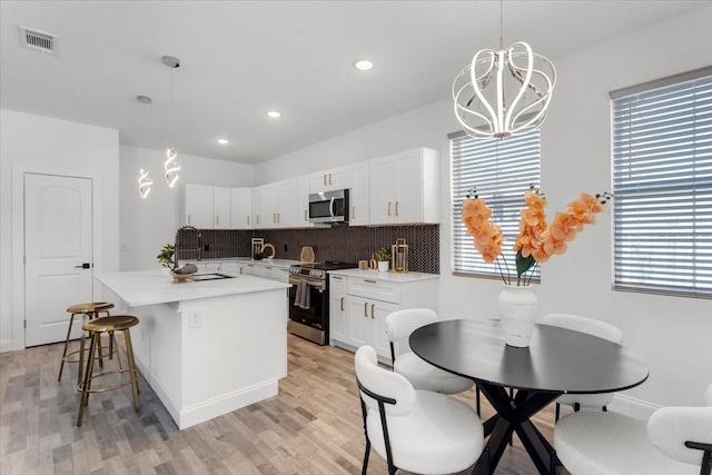 kitchen featuring visible vents, a kitchen island, stainless steel appliances, a kitchen bar, and backsplash