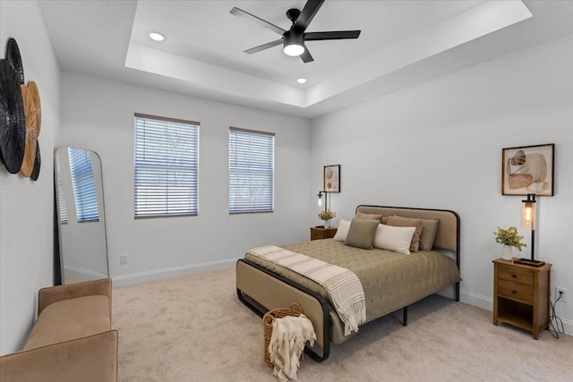 bedroom with a tray ceiling, recessed lighting, light carpet, ceiling fan, and baseboards