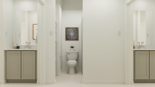 full bath featuring a sink, baseboards, toilet, and two vanities