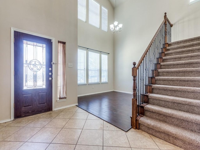 entrance foyer with baseboards, stairway, light tile patterned flooring, and a notable chandelier