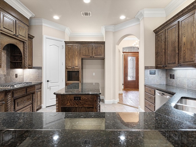 kitchen with arched walkways, stainless steel appliances, a kitchen island, visible vents, and dark stone counters