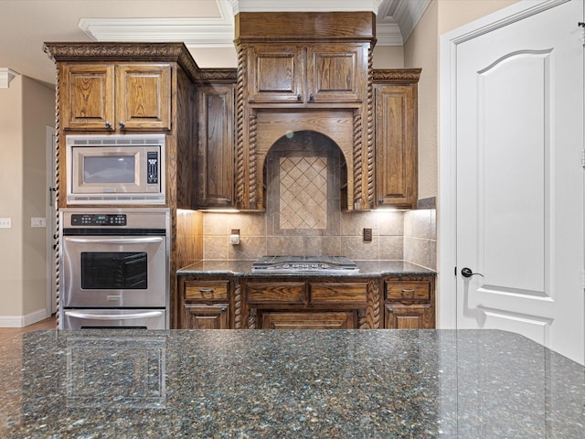 kitchen with appliances with stainless steel finishes, dark stone countertops, crown molding, backsplash, and a warming drawer