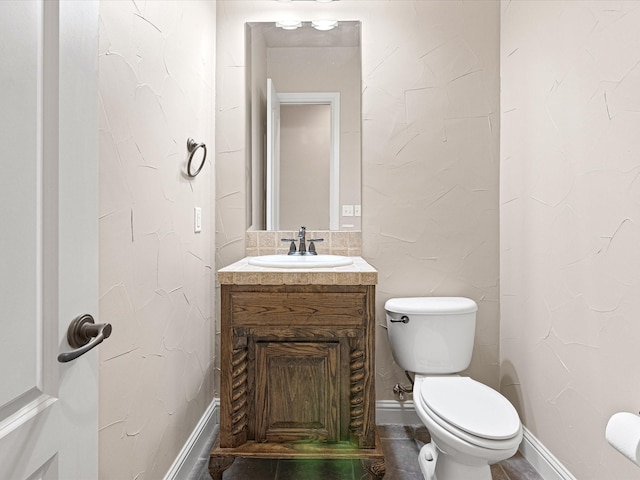 half bathroom featuring toilet, vanity, and baseboards