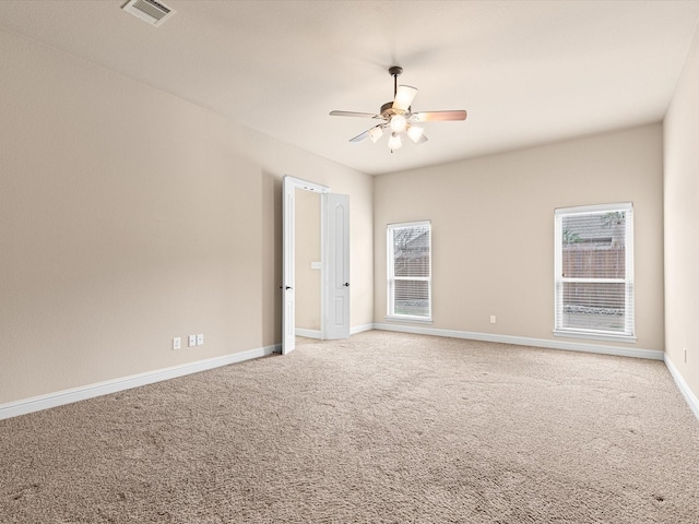 carpeted empty room with ceiling fan, plenty of natural light, visible vents, and baseboards