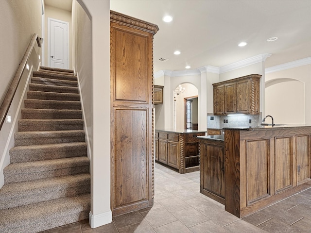 kitchen featuring tasteful backsplash, arched walkways, dark countertops, a peninsula, and crown molding