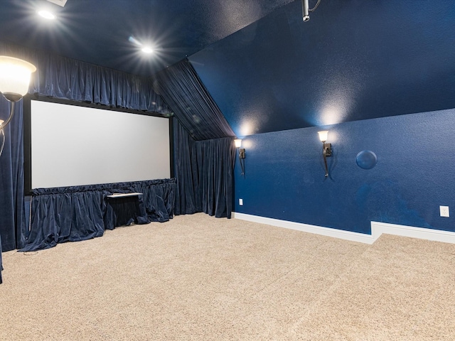 carpeted home theater room featuring lofted ceiling and baseboards