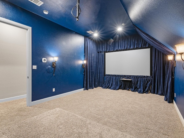 carpeted home theater with lofted ceiling, visible vents, a textured wall, a textured ceiling, and baseboards