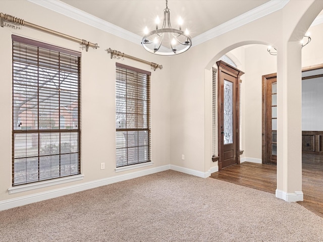 empty room with carpet floors, arched walkways, ornamental molding, and an inviting chandelier