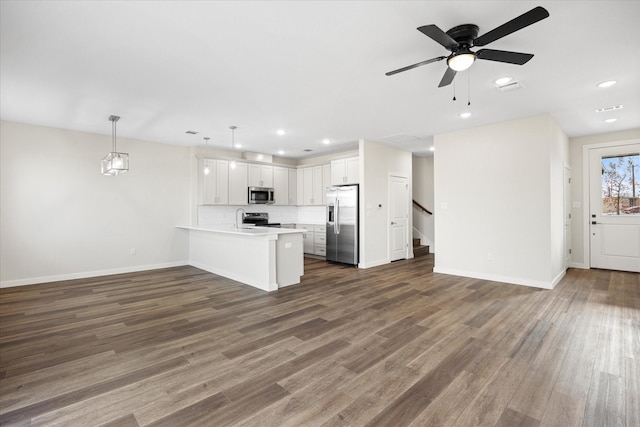 kitchen with pendant lighting, stainless steel appliances, light countertops, open floor plan, and white cabinetry