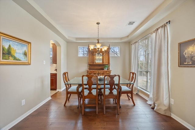 dining space featuring dark wood-style floors, arched walkways, visible vents, and baseboards