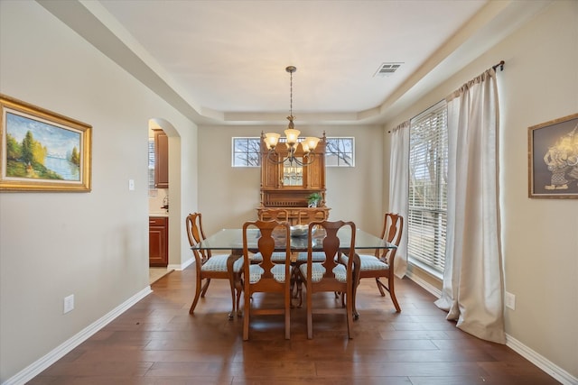 619 Loch View Ct, Rockwall, TX 75087 - dining area with arched walkways, a chandelier, dark wood-type flooring, and a tray ceiling
