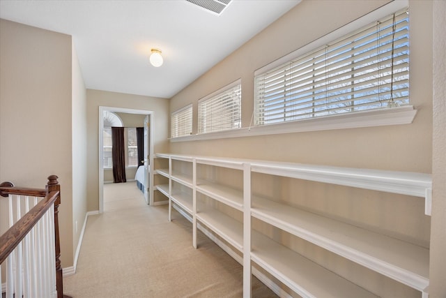 corridor featuring light carpet, baseboards, and visible vents