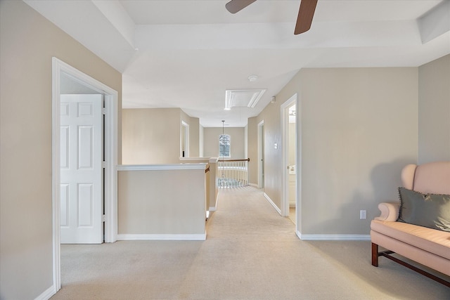 hallway featuring attic access, baseboards, light colored carpet, and an upstairs landing