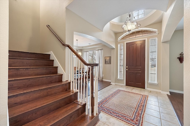 entrance foyer with light tile patterned floors, stairway, a chandelier, and baseboards