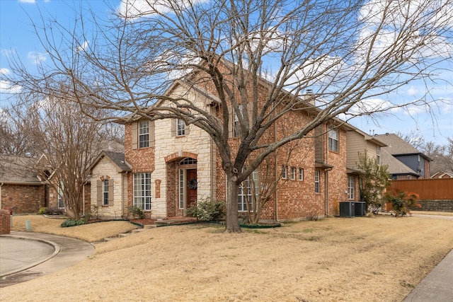 view of front of property with stone siding, a chimney, fence, a front yard, and brick siding