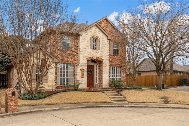 view of front of house featuring stone siding, fence, and brick siding