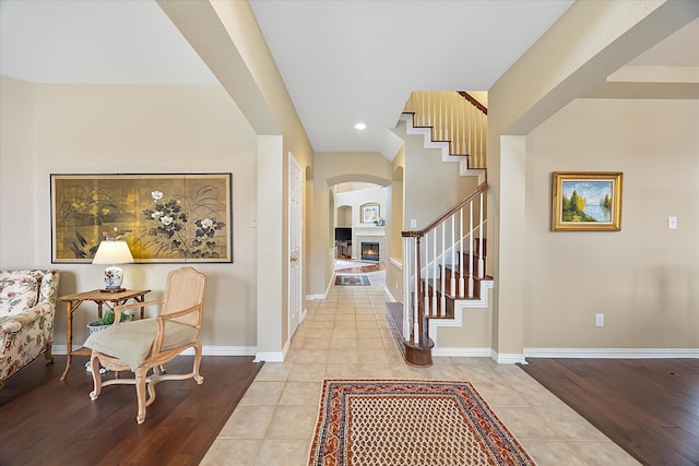 619 Loch View Ct, Rockwall, TX 75087 - living room featuring a tiled fireplace, ceiling fan, wood finished floors, a towering ceiling, and arched walkways