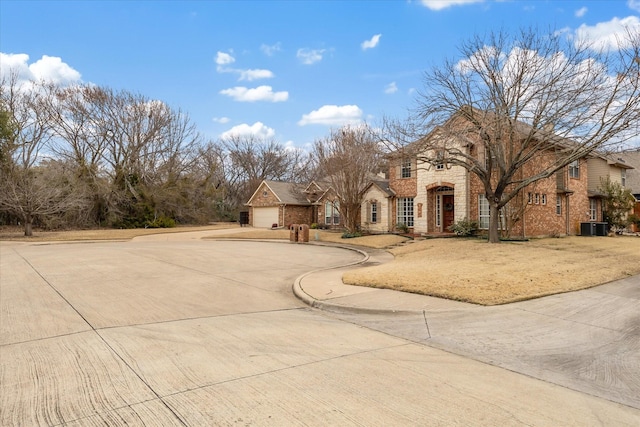 view of front of house with a garage, stone siding, brick siding, and central AC