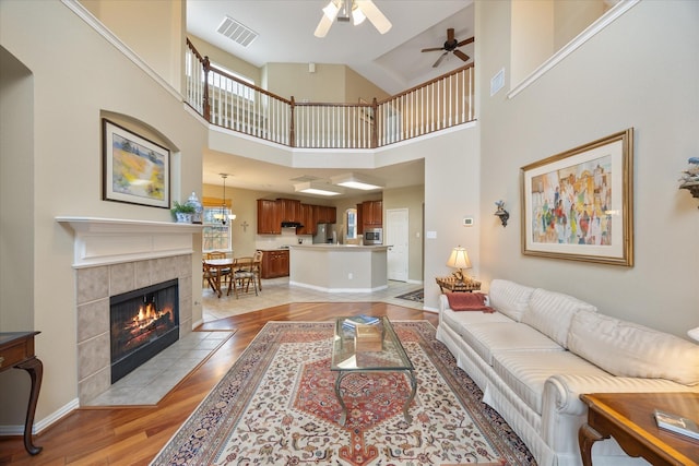 619 Loch View Ct, Rockwall, TX 75087 - living area with a ceiling fan, light wood-style floors, a tile fireplace, a high ceiling, and baseboards