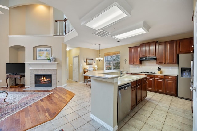 619 Loch View Ct, Rockwall, TX 75087 - kitchen with stainless steel appliances, a sink, light countertops, light tile patterned flooring, and a fireplace